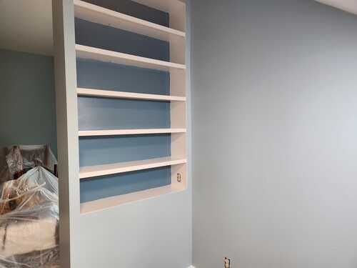 A room with a bed and shelves in it.