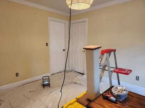 A room with a ladder and a light on the floor.