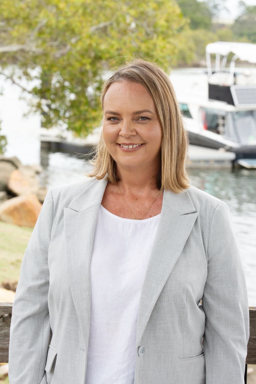 A Woman With Blonde Hair Smiles Outdoors — Daly Legal In Macksville, NSW