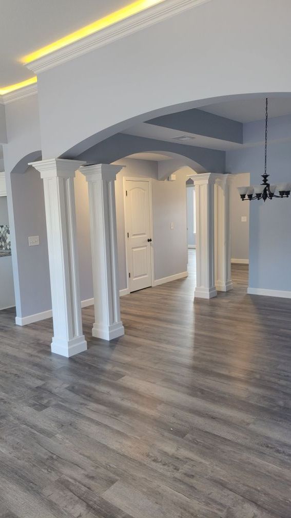 Interior view with gray walls, white columns, wood-look flooring, and a chandelier.