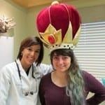 Two people posing indoors, one wearing a large red-and-gold crown costume headpiece.