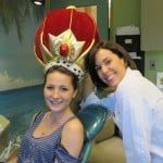 Two smiling people in costume, one wearing a red crown-like headpiece, posing indoors