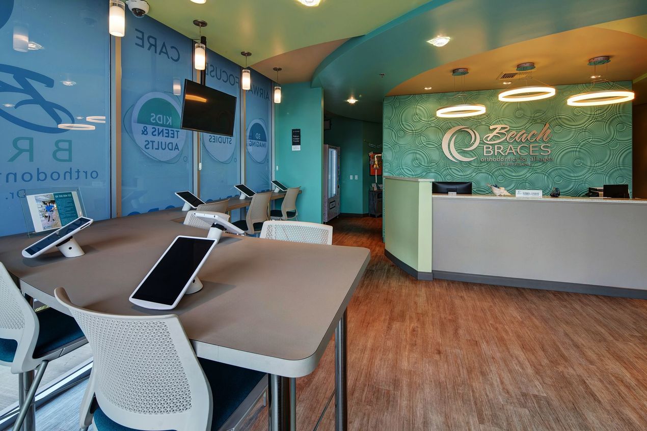 Modern office lobby with teal walls, reception desk, and seating area with tables and chairs