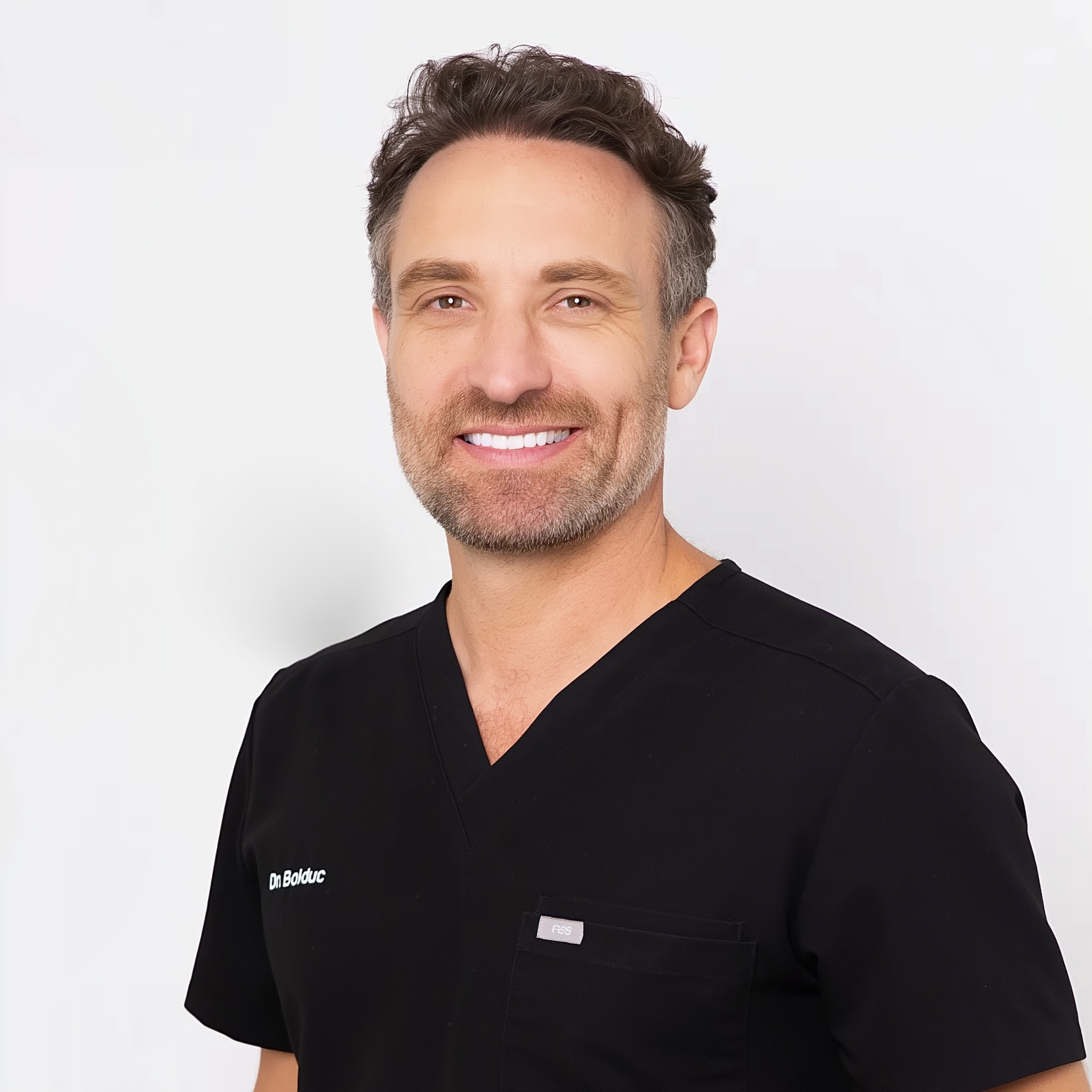 Smiling person in black medical scrubs on a white background