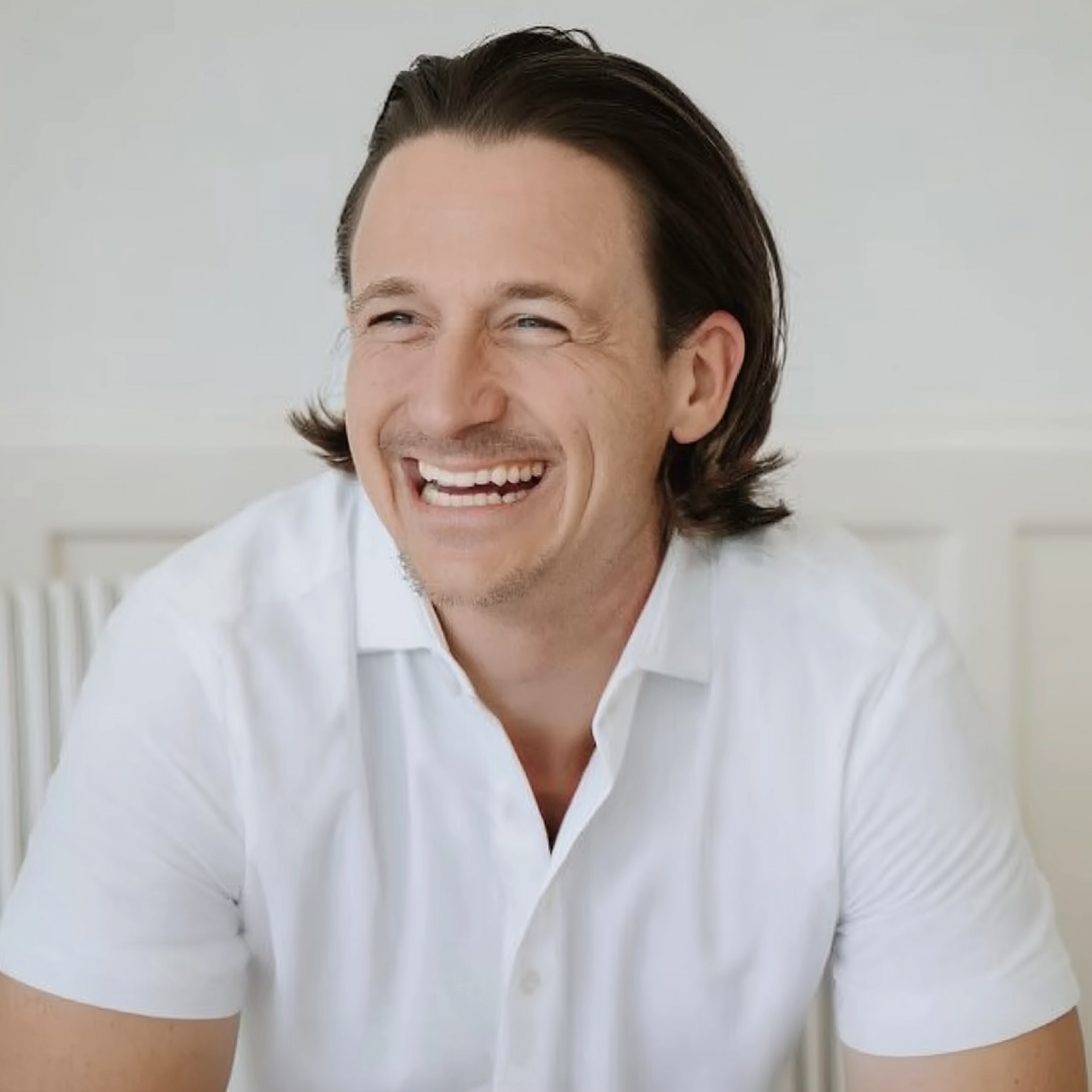 Smiling man in a white shirt against a light background