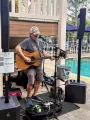 Street musician playing acoustic guitar beside a pool at an outdoor venue