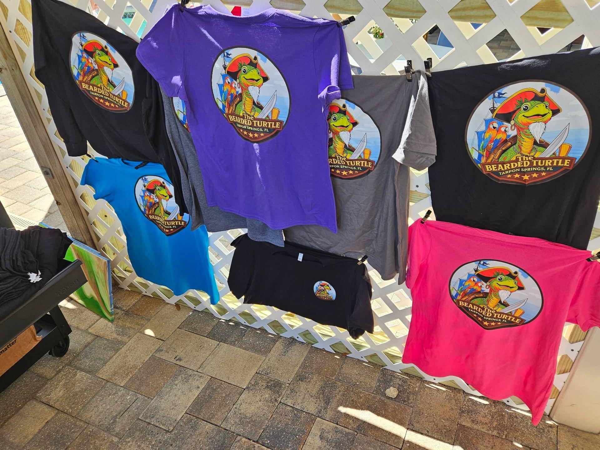 Colorful graphic T-shirts hanging on a chain-link fence at an outdoor market