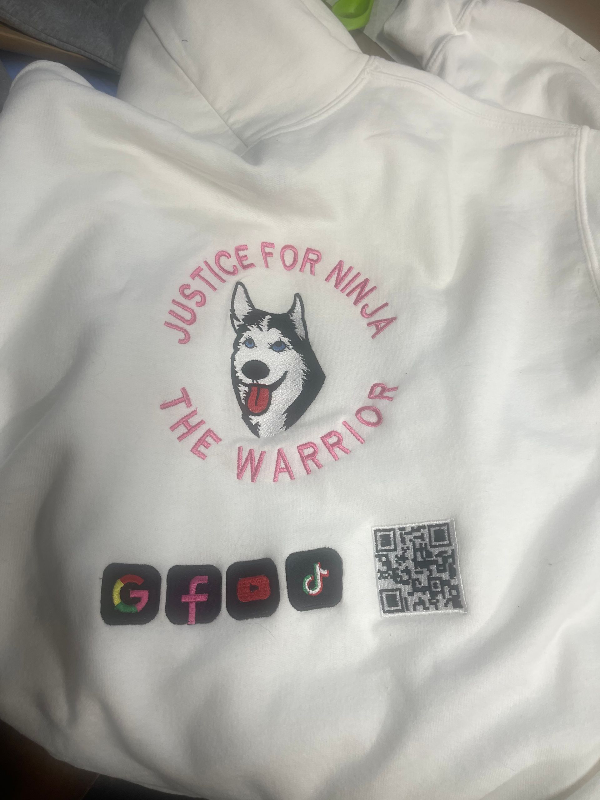 A white hoodie featuring an embroidered husky, 