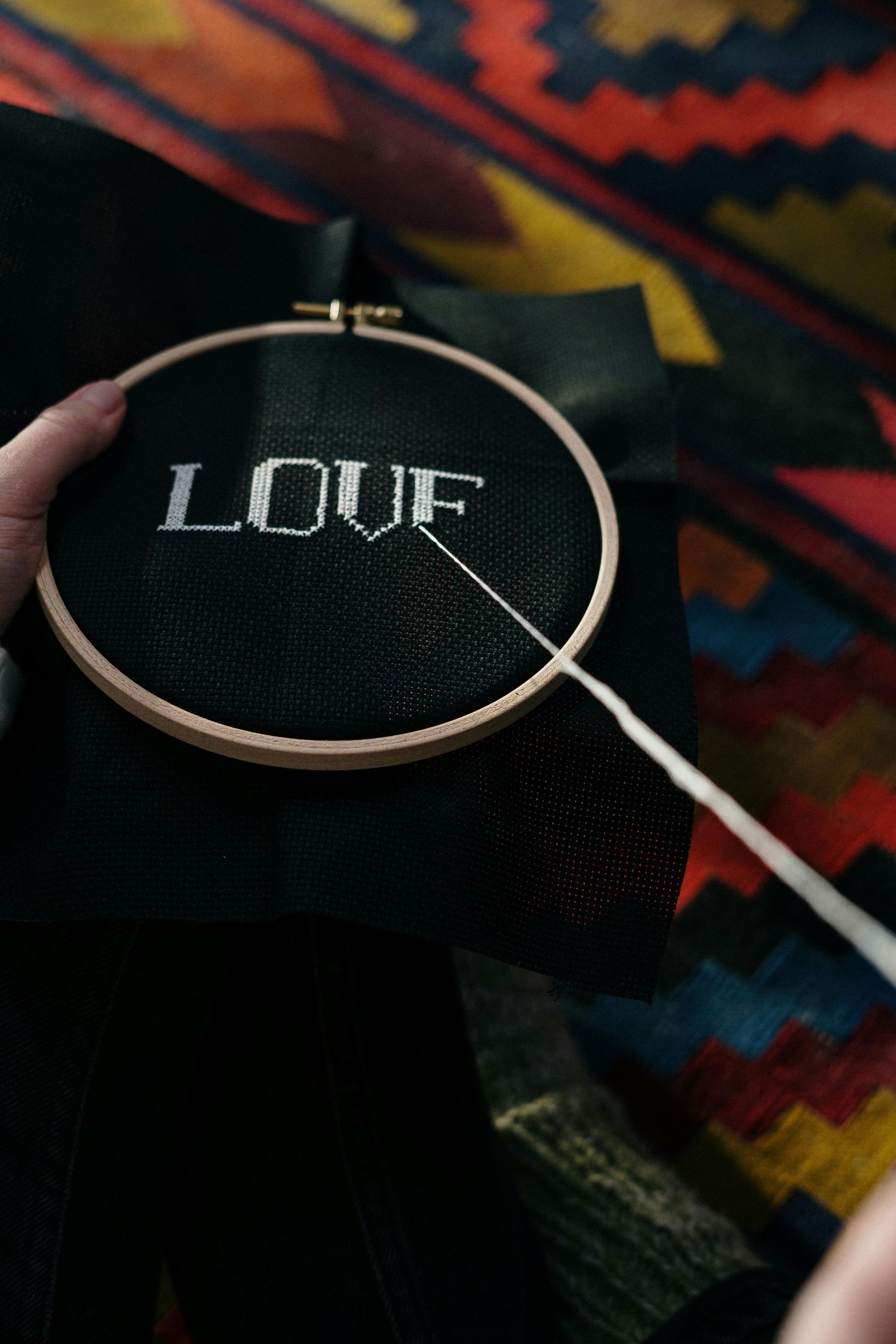 A person cross-stitching the word 