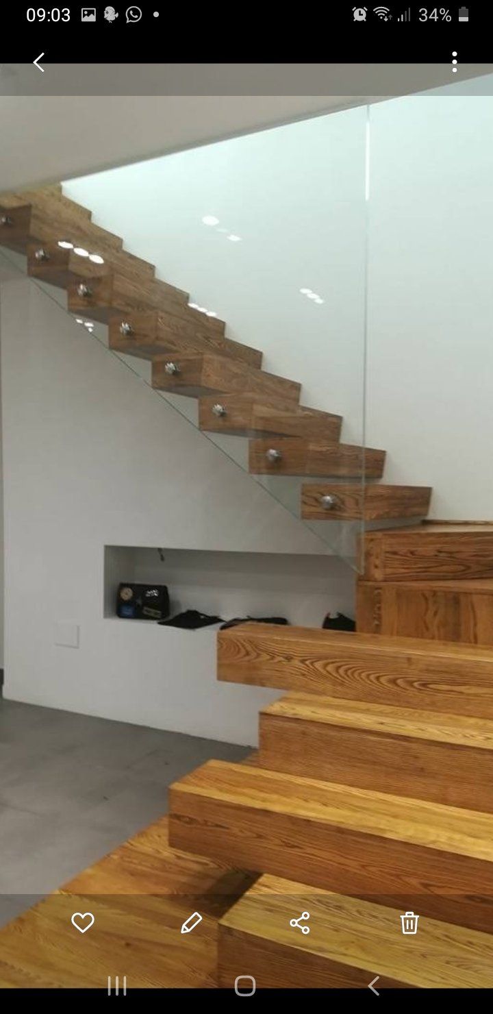 Scala sospesa in legno con ringhiera in vetro in un interno minimalista bianco