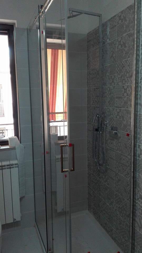 Box doccia moderno con porte in vetro e pareti piastrellate in un bagno