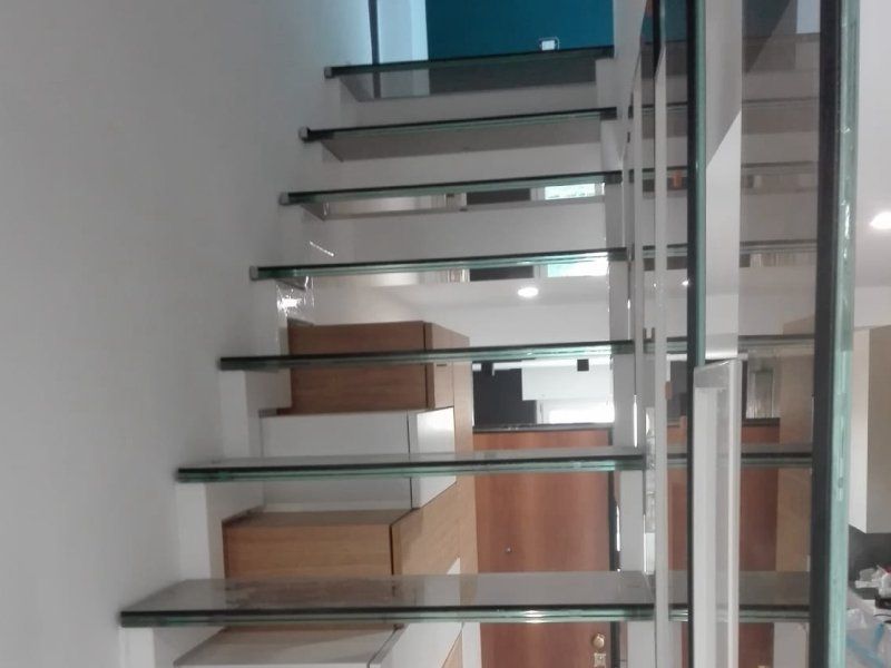 Scala in vetro con gradini in metallo e scatole di cartone in un interno moderno.