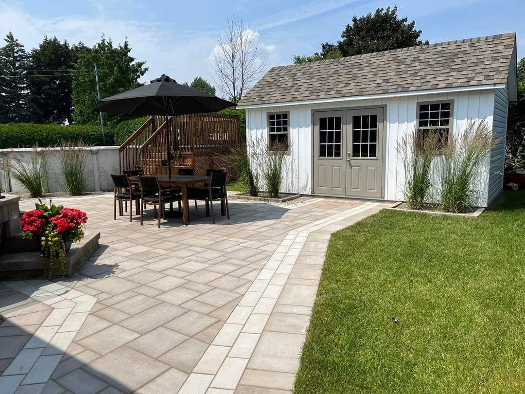 Terrasse arrière avec ensemble de salle à manger, abri de jardin et pelouse aménagée par une journée ensoleillée.