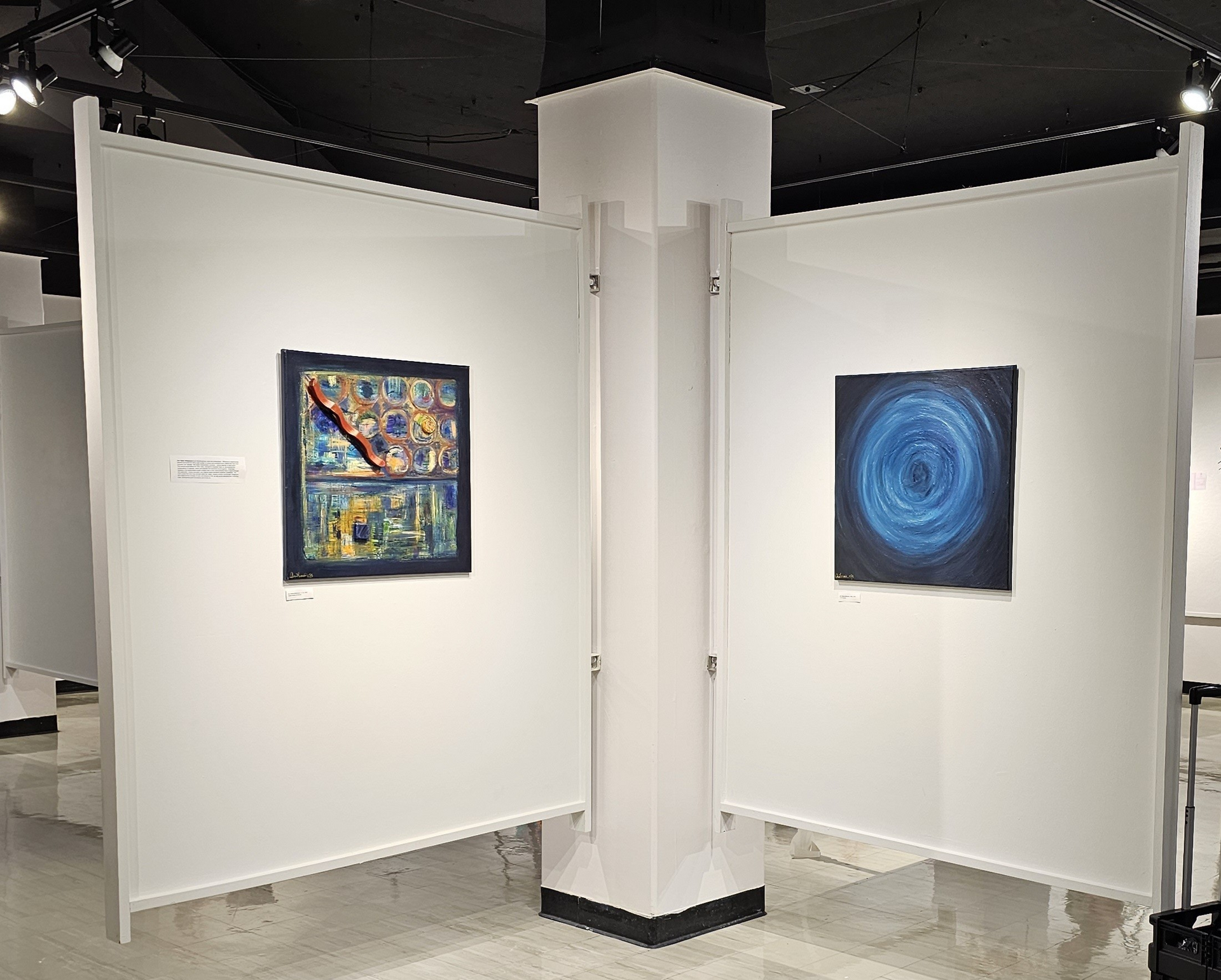 Two framed abstract artworks displayed on white gallery walls in an exhibition space.
