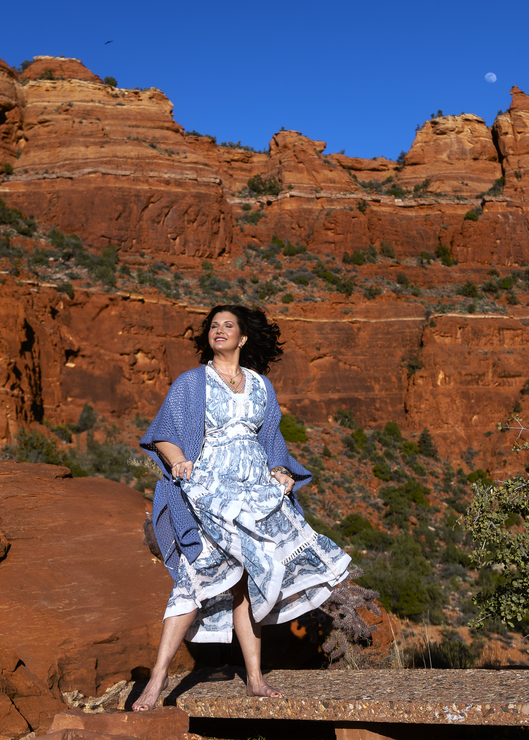 Woman in white outfit and sunglasses posing outdoors with the name “ANN MARIA” below.