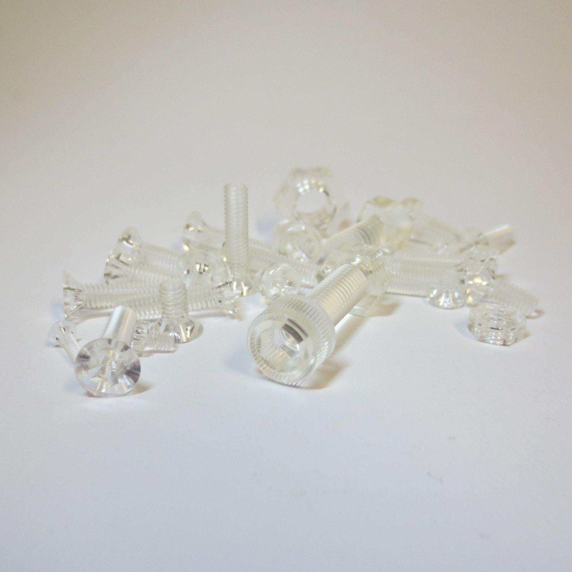 Ein Haufen durchsichtiger Plastikschrauben auf einer weißen Oberfläche