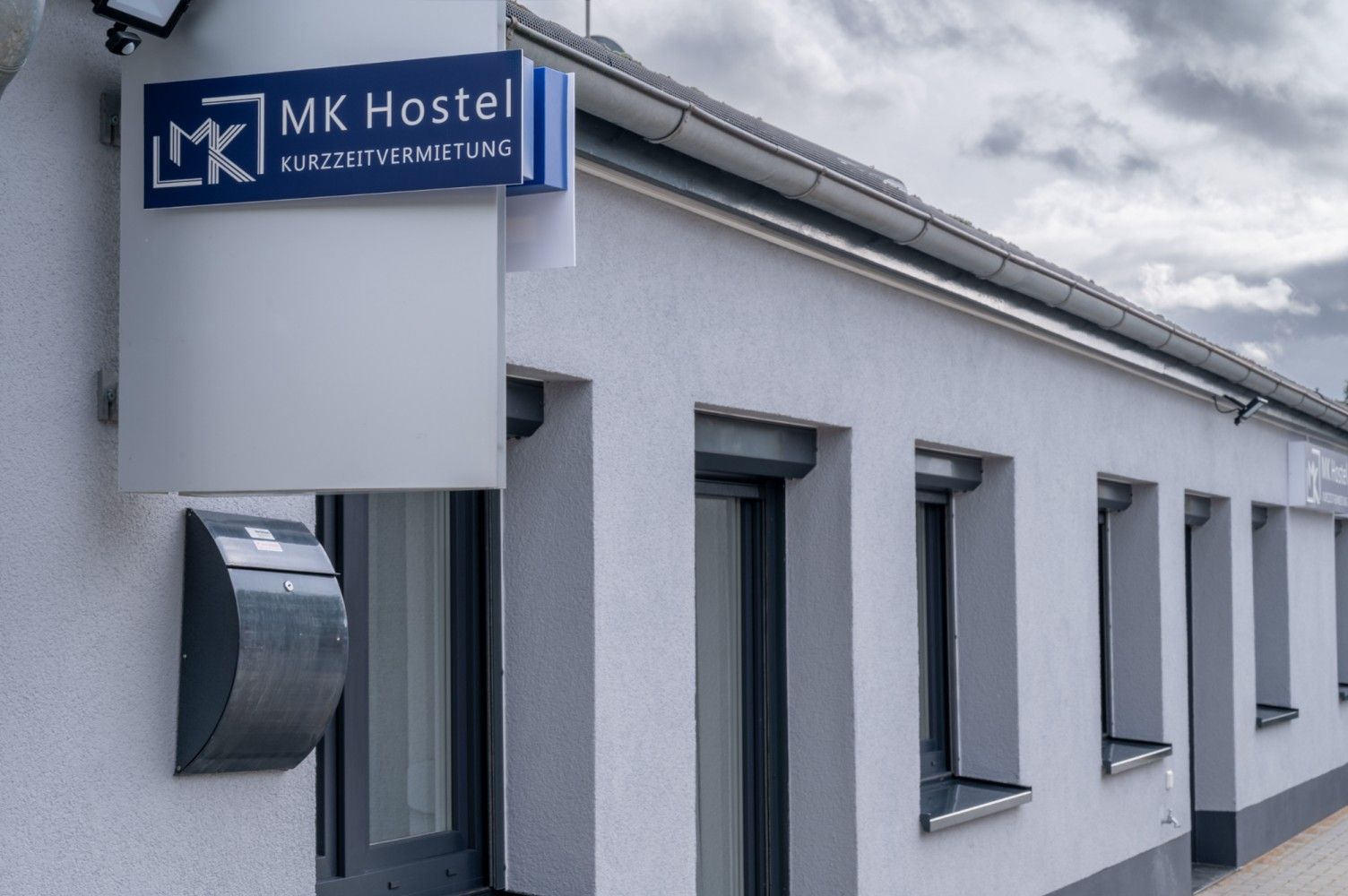 MK Hostel building exterior with sign and windows; overcast sky.