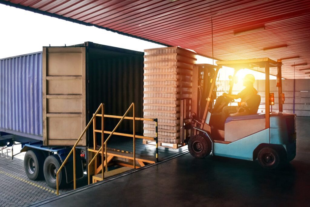 Forklift Loading Pallets Into a Shipping Container at a Warehouse Dock — Premier Removals & Storage In Boambee, NSW