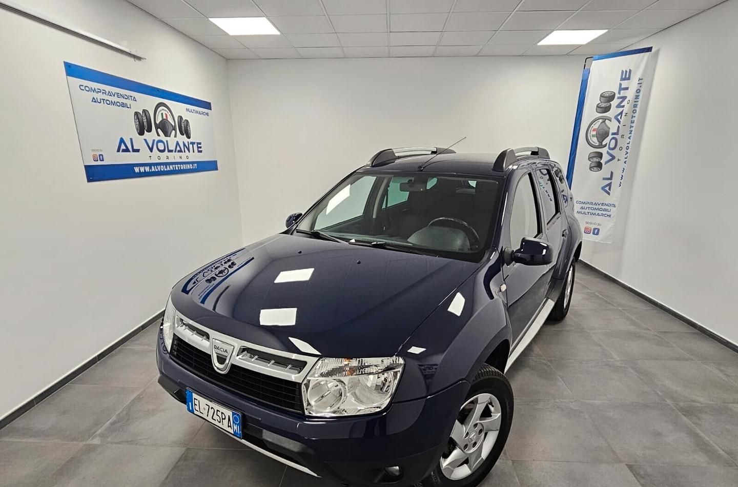 Una Chevrolet Spark nera parcheggiata all'interno di uno showroom di una concessionaria ben illuminato, con pareti bianche e pavimenti piastrellati.