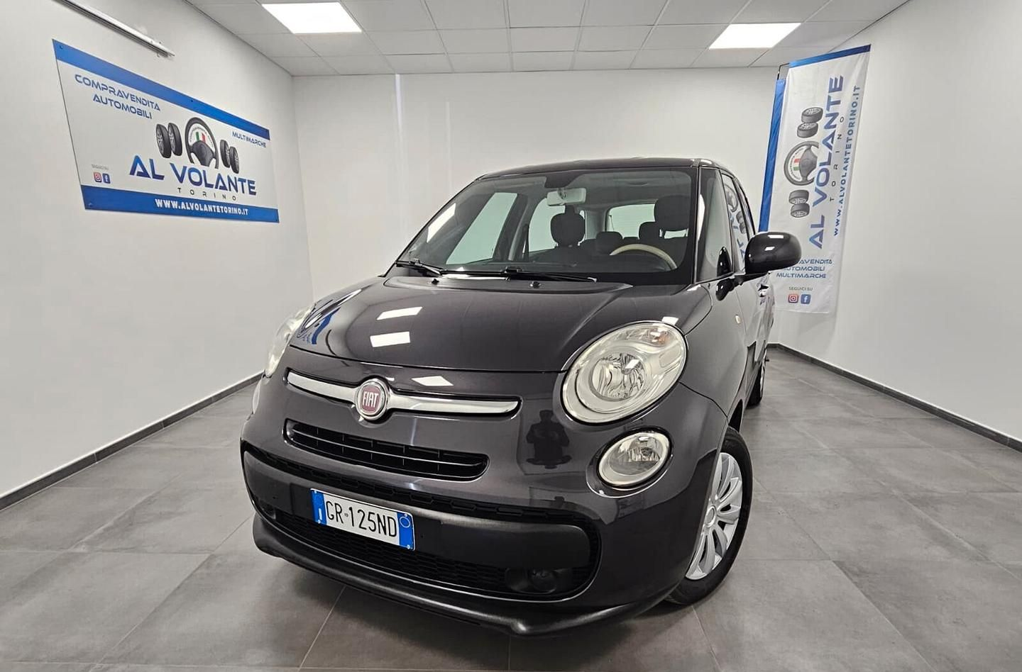 Una Citroën C3 grigio scuro parcheggiata in uno showroom luminoso con pareti bianche e uno striscione con il logo sulla parete.