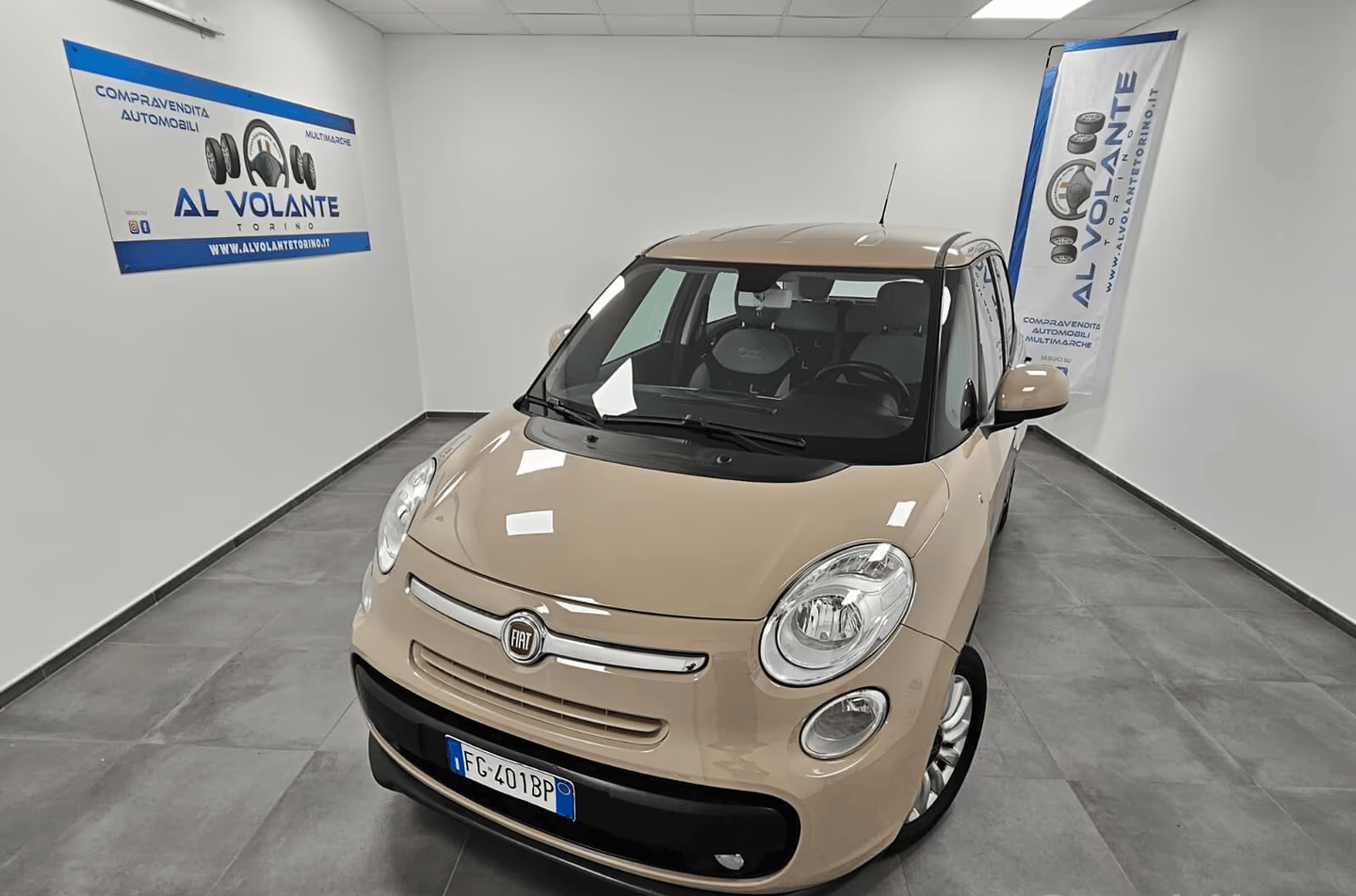 Una Daihatsu Terios grigia parcheggiata in uno showroom interno luminoso con pareti bianche e striscioni pubblicitari.