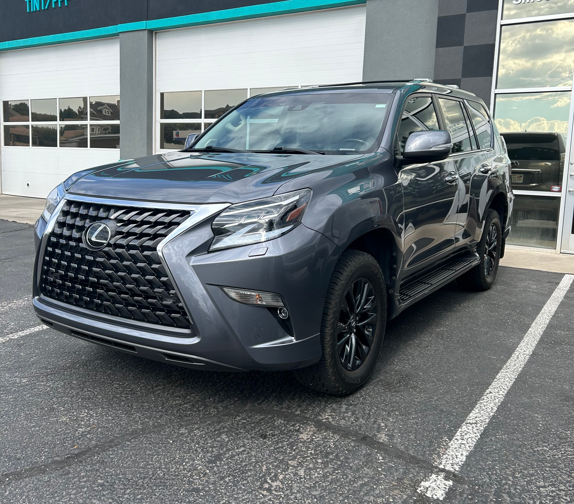 Gray Lexus GX SUV parked outside a building with black wheels and grill.