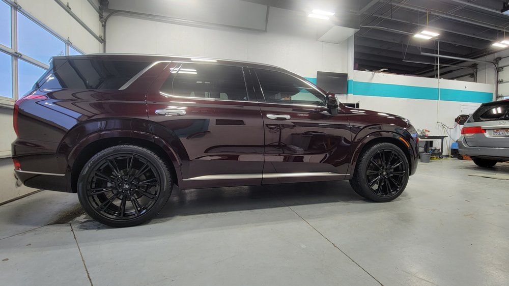 Maroon SUV with black rims parked inside a garage.
