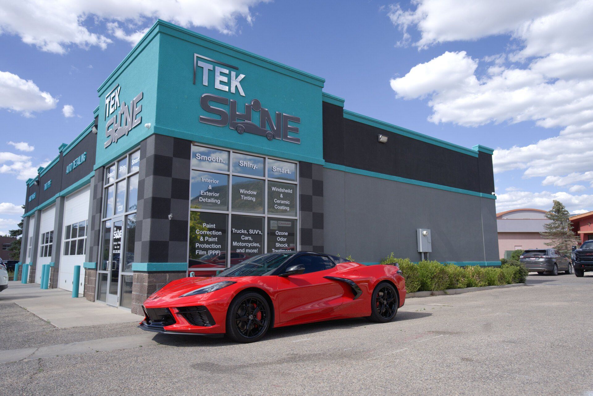 A red sports car is parked in front of a tek shine car wash.