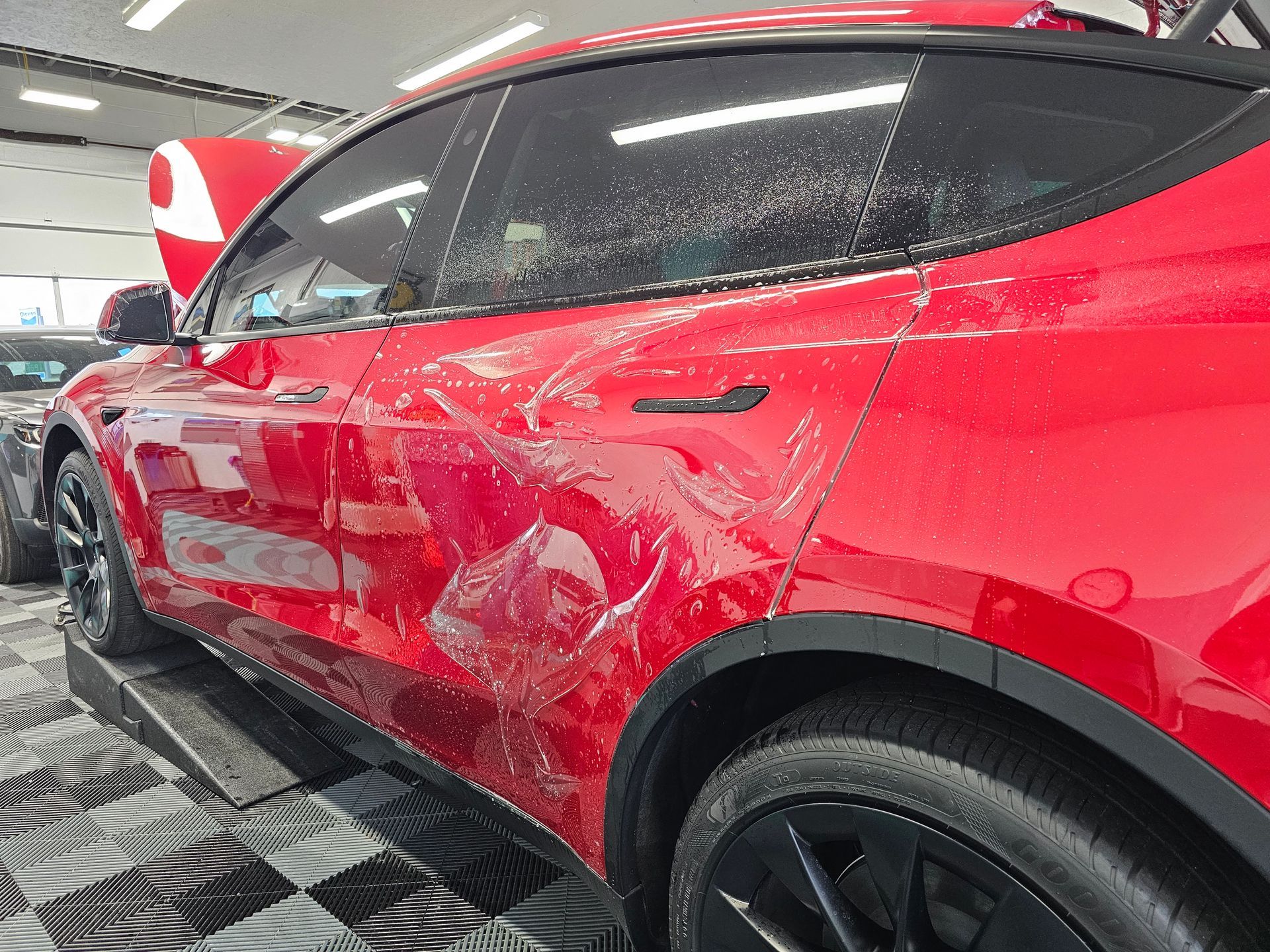 Red SUV with severe side-panel damage in a garage or repair shop