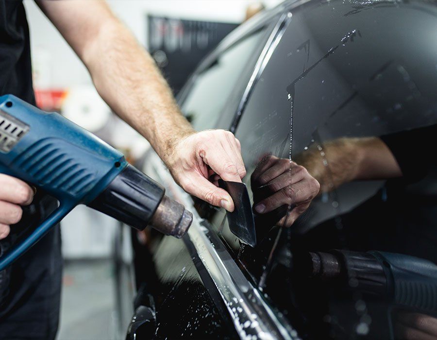 A man is applying tinted glass to a car window.