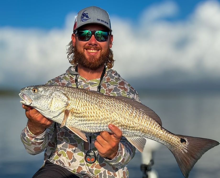 A man is holding a large fish in his hands.