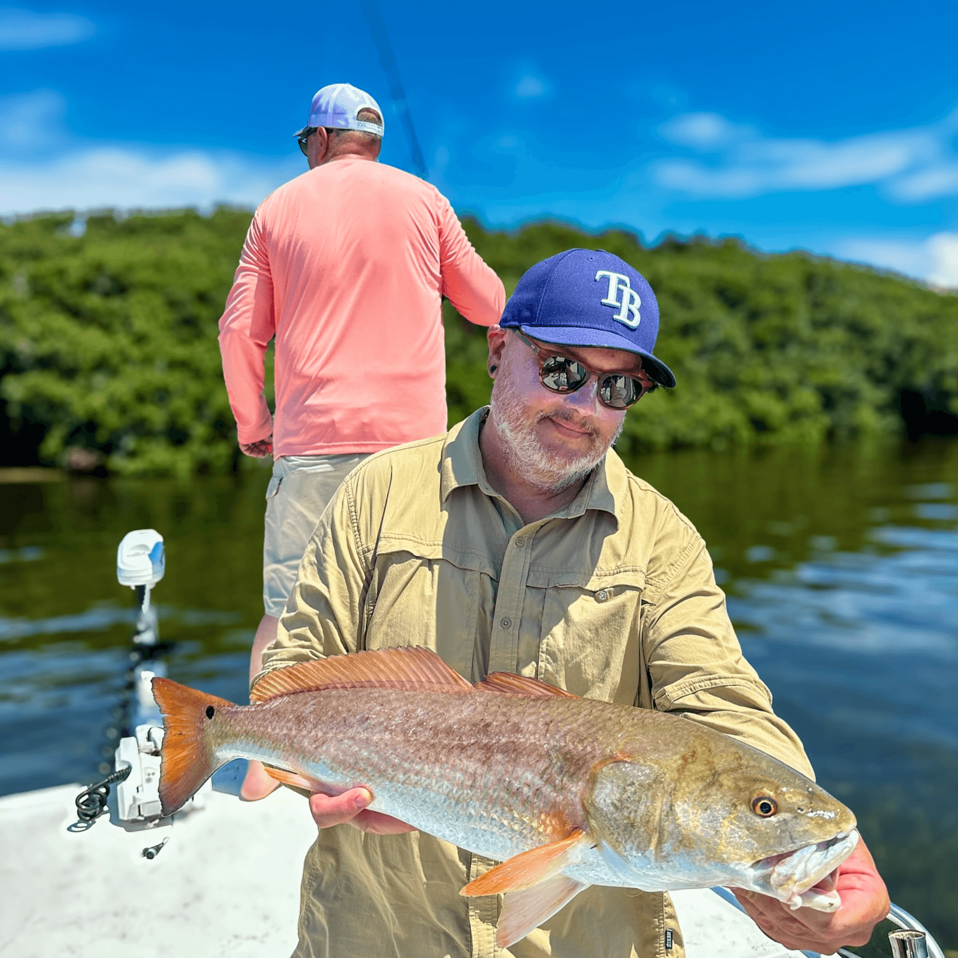 A man is holding a large fish on a boat.
