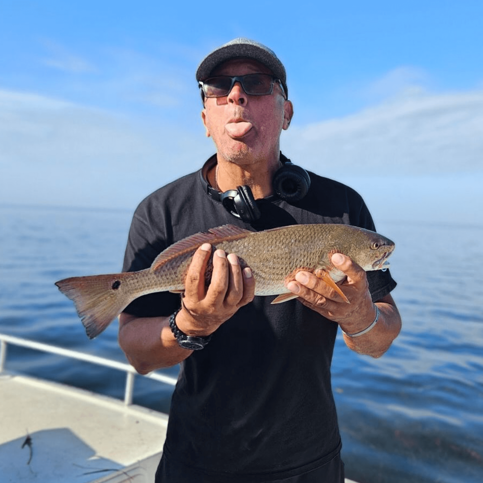 A man is holding a large fish in his hands on a boat