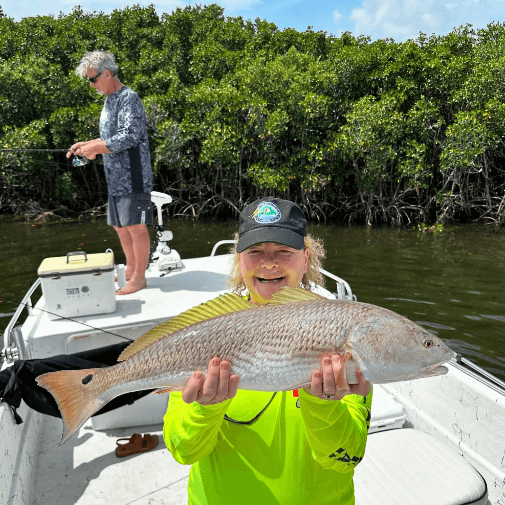 A woman is holding a large fish on a boat.