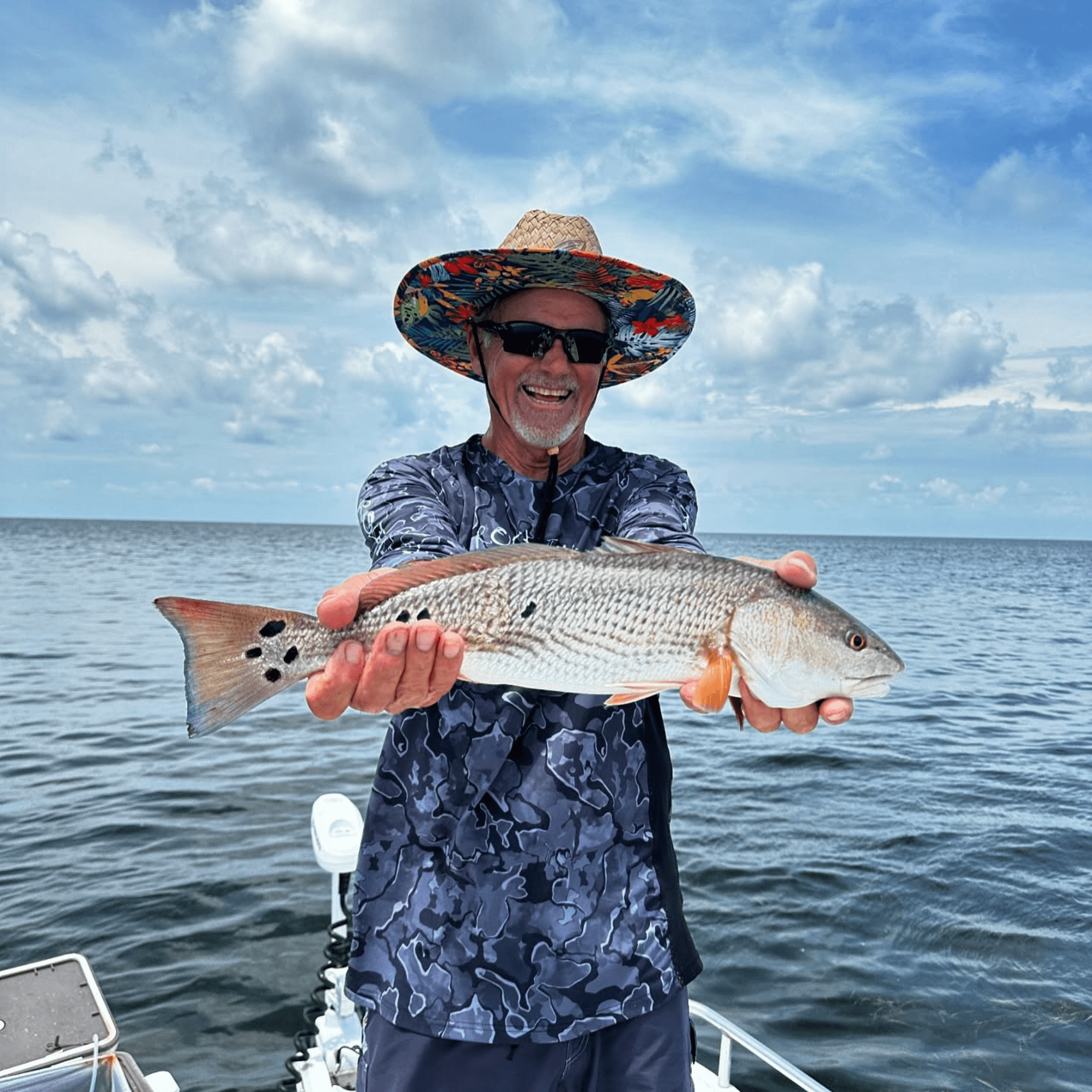 A man is holding a large fish in his hands on a boat.
