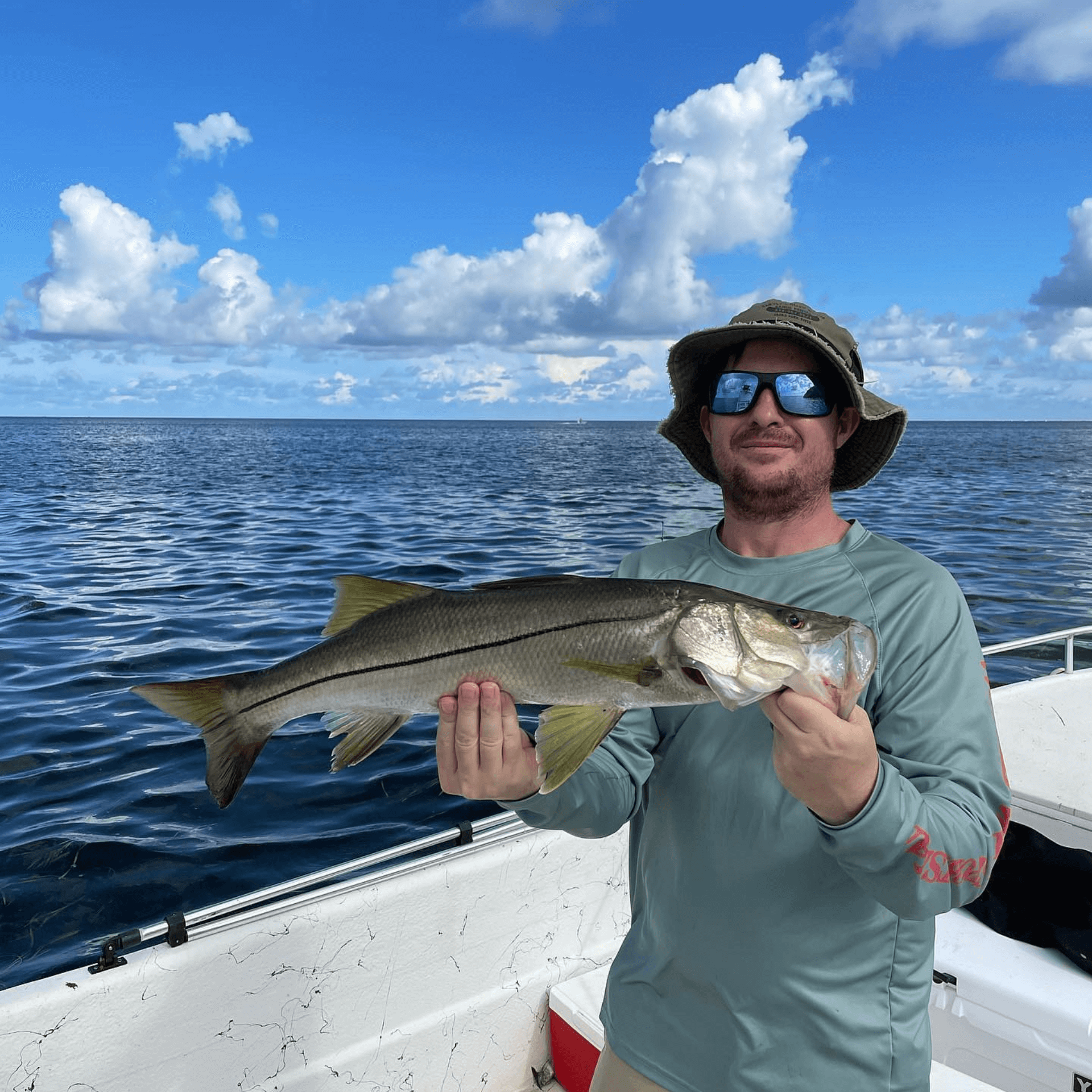 A man is holding a Snook caught on a flats fishing charter in Florida
