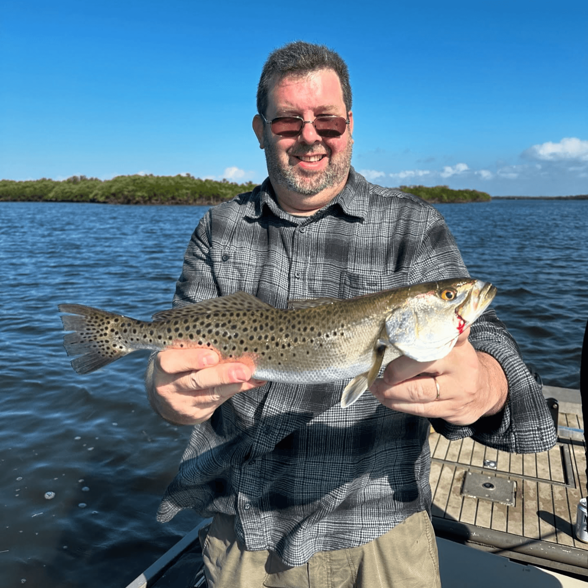 A man is holding a fish in his hands on a boat.