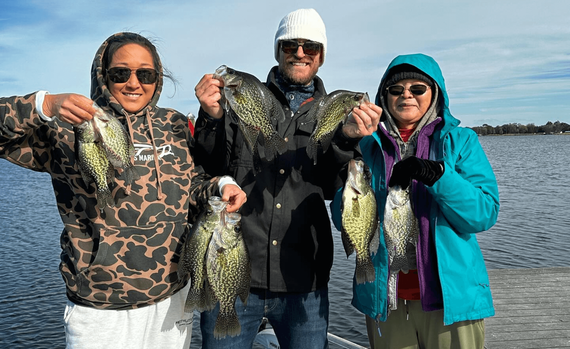 A group of people are standing on a boat holding fish.