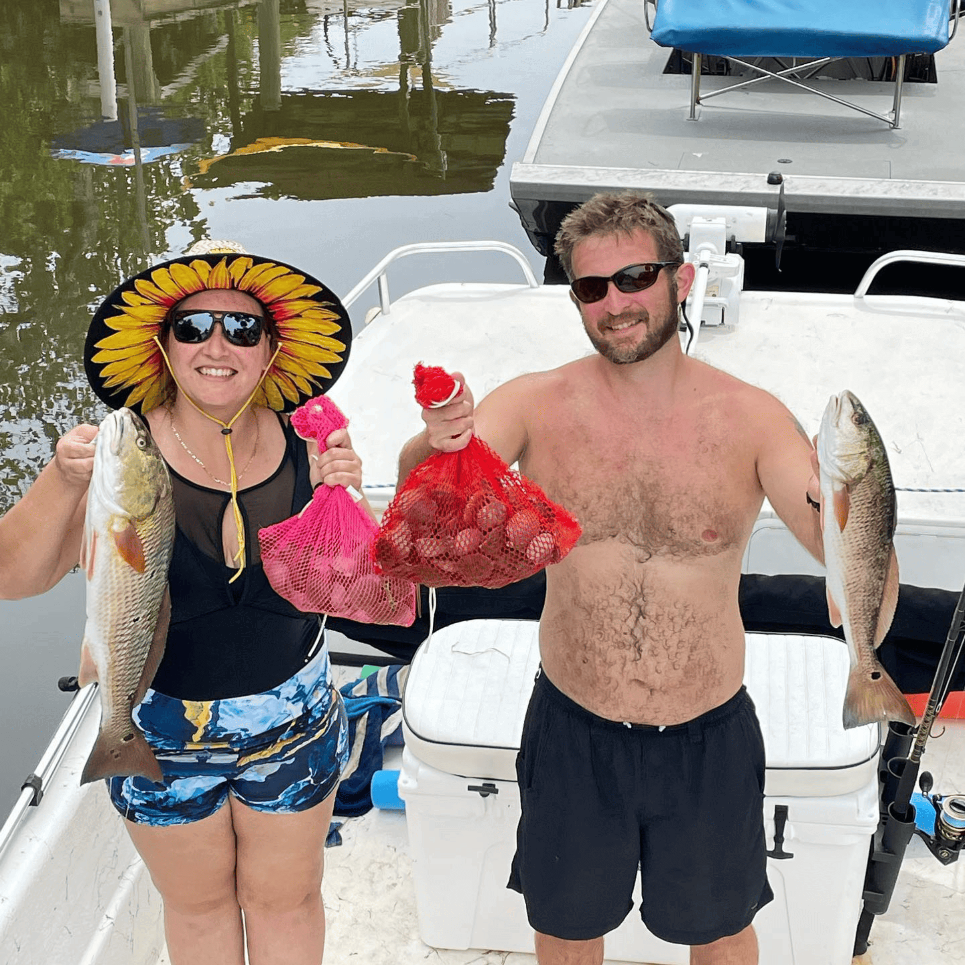 A man and a woman are standing on a boat holding fish and scallops