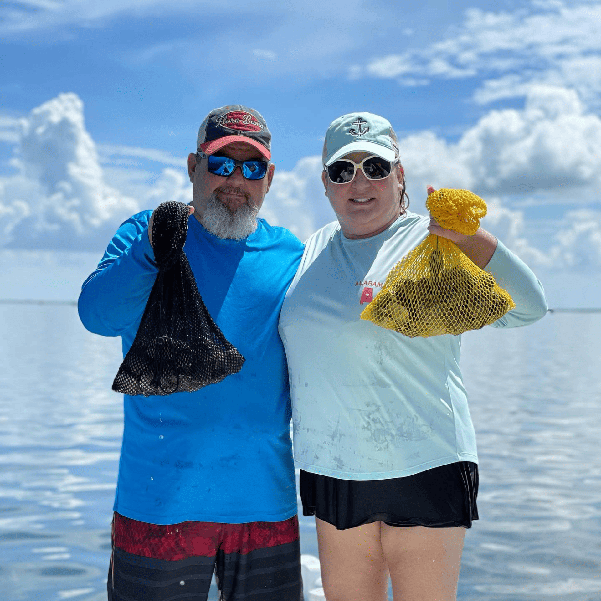A man and a woman are standing on a boat holding bags of oysters.
