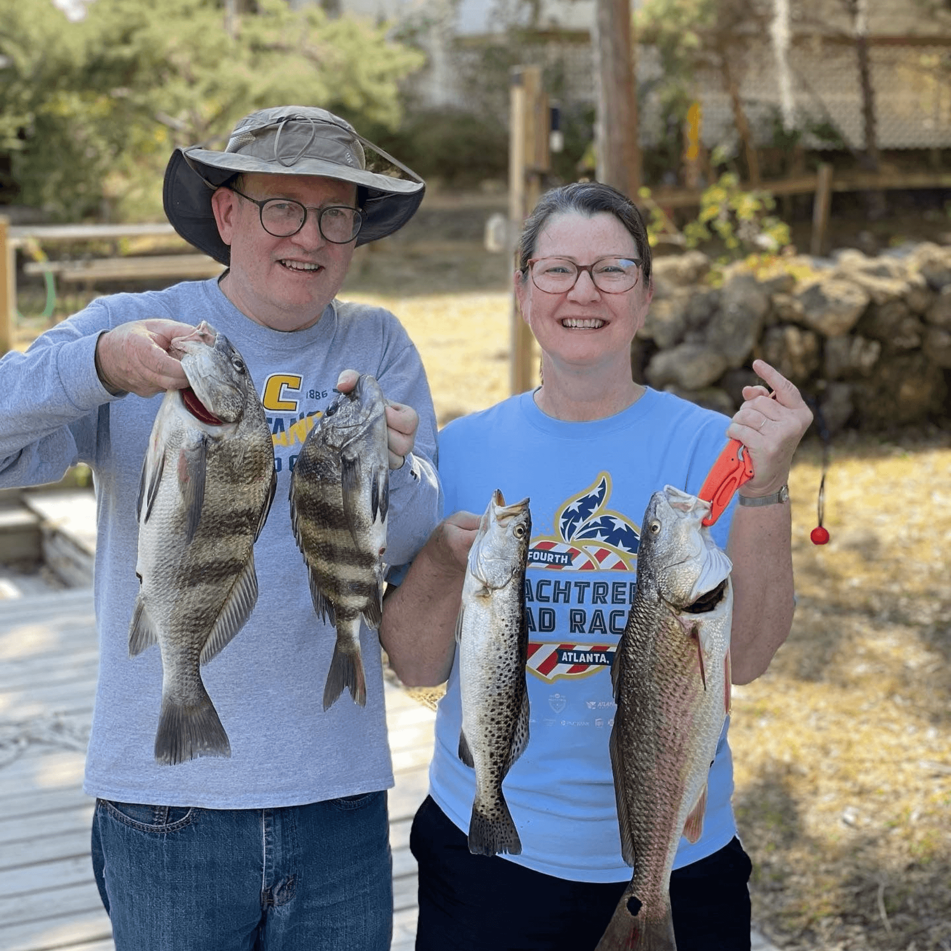 A man and a woman are holding two fish in their hands.