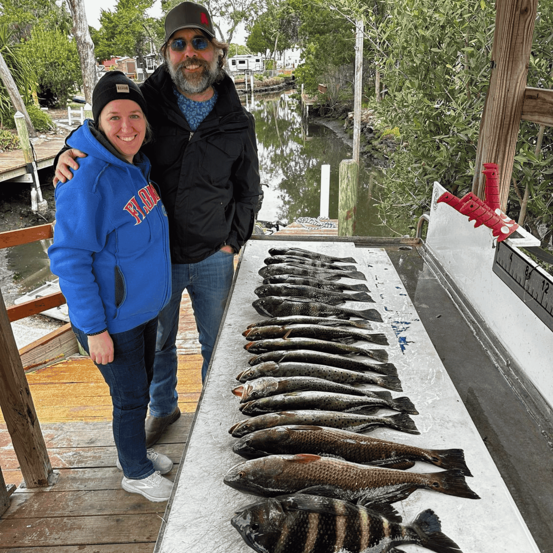 A man and a woman are standing next to a table full of fish.