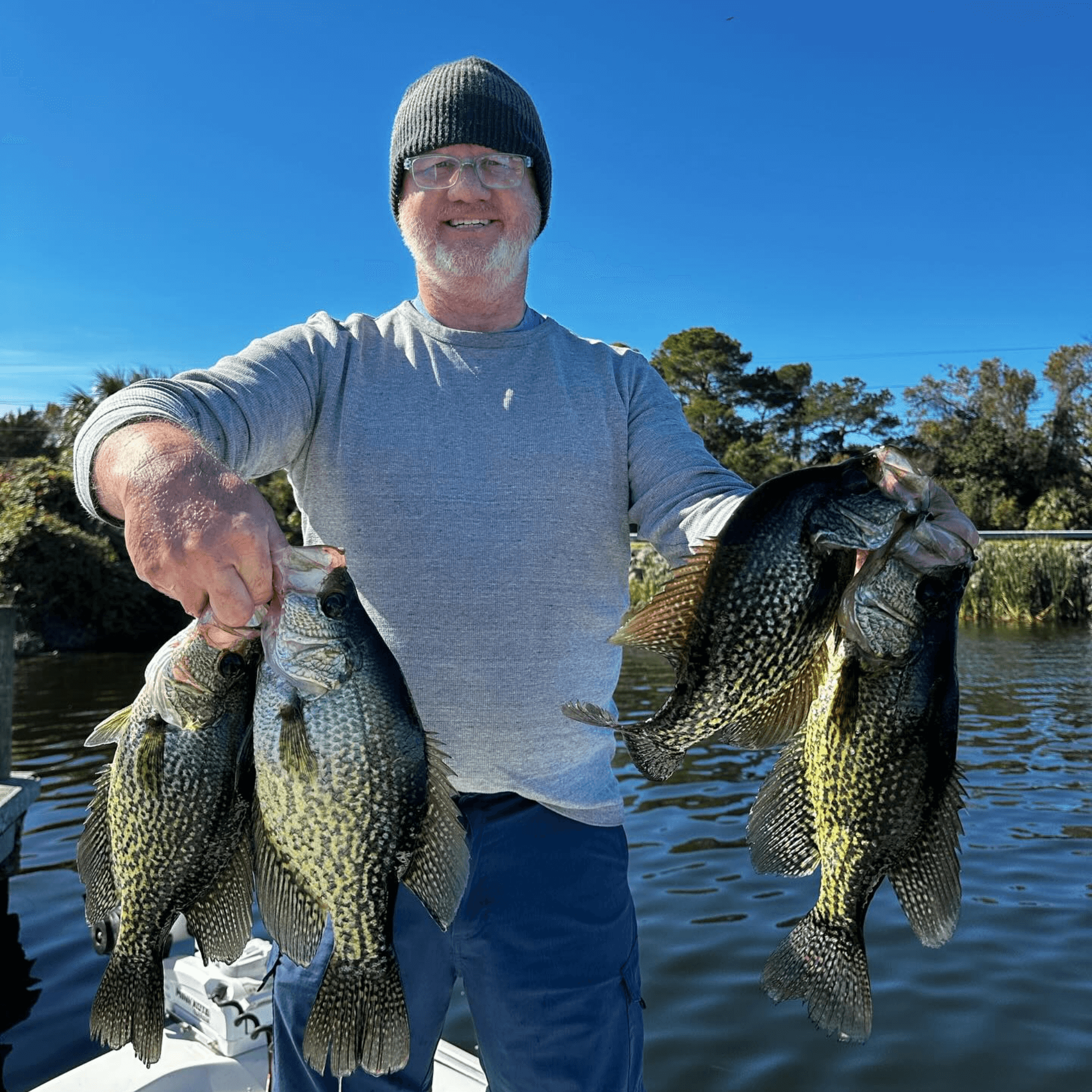 A man is holding three fish in his hands on a boat.