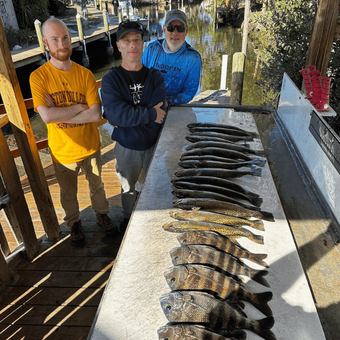 Three men are standing next to a table full of fish.