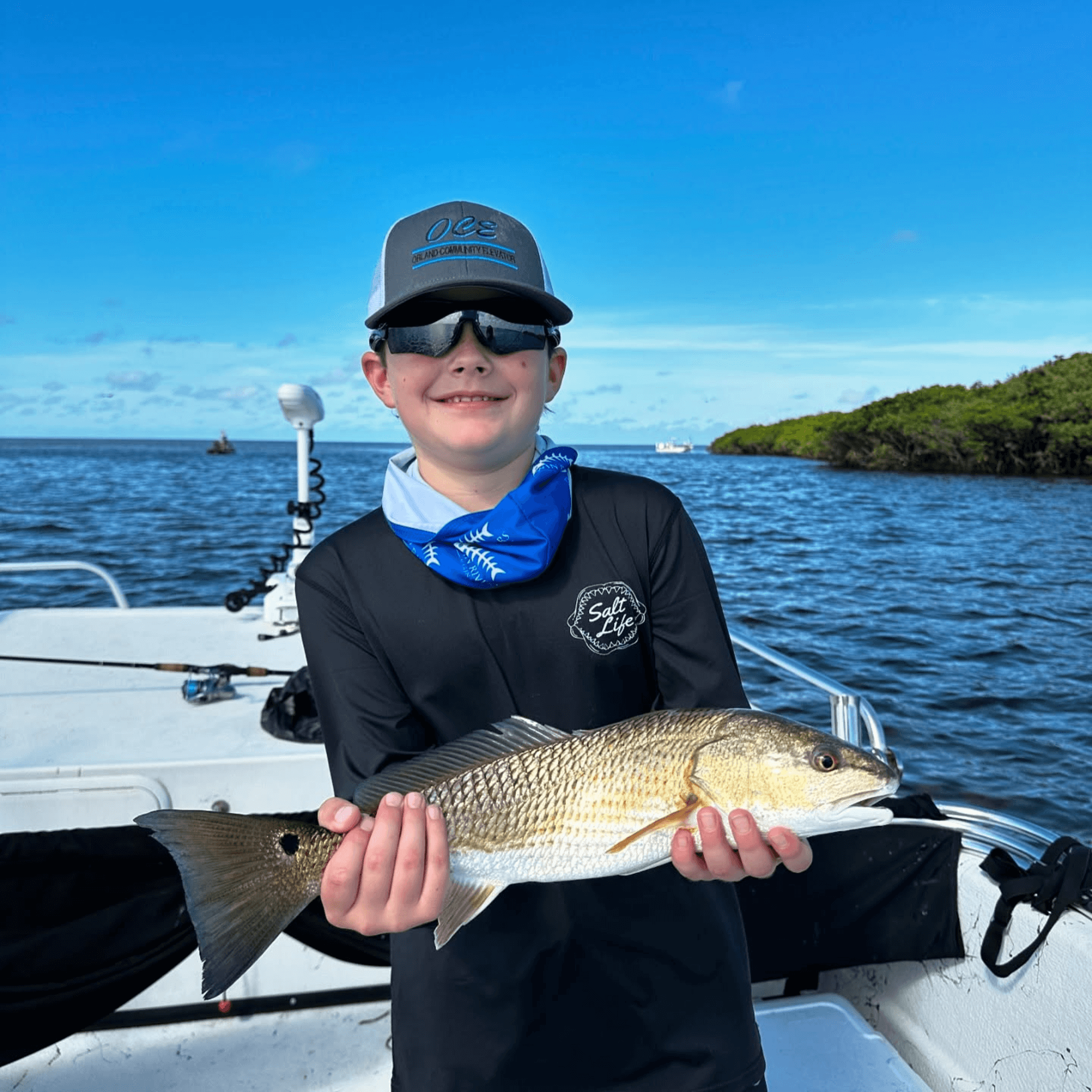 A young boy is holding a large fish on a boat.