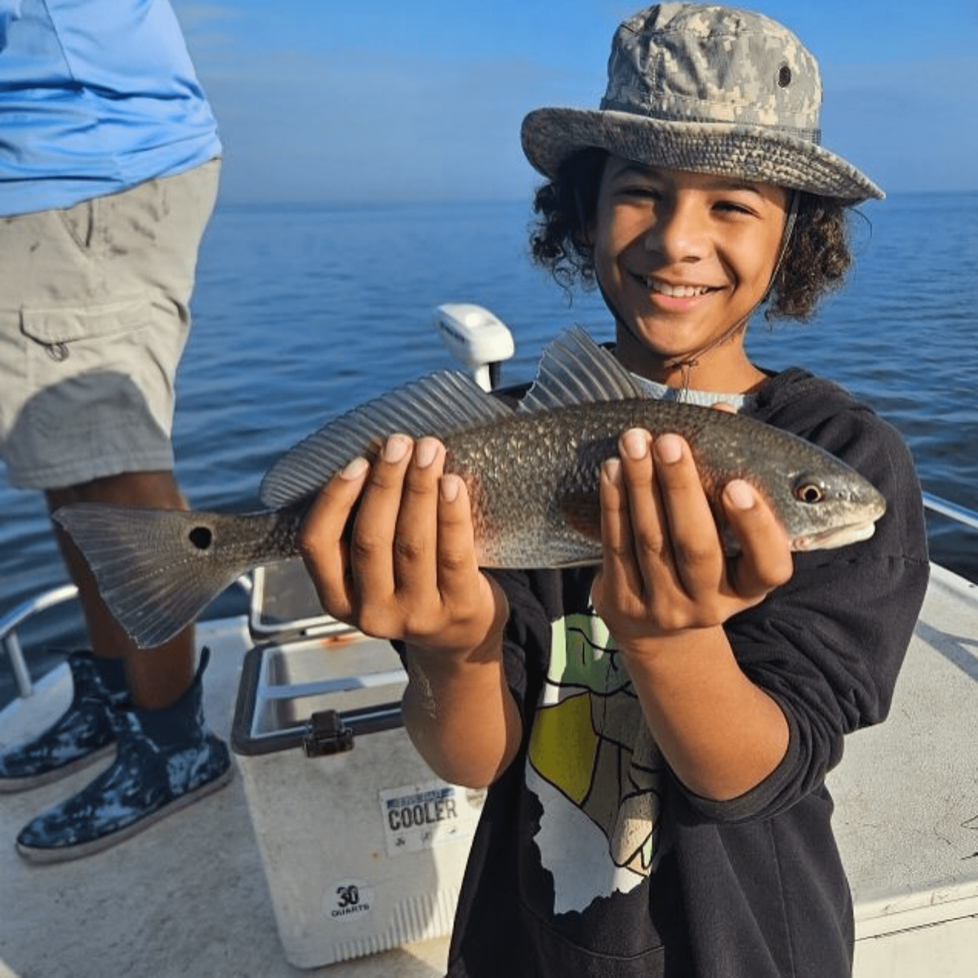A young boy is holding a fish in his hands on a boat