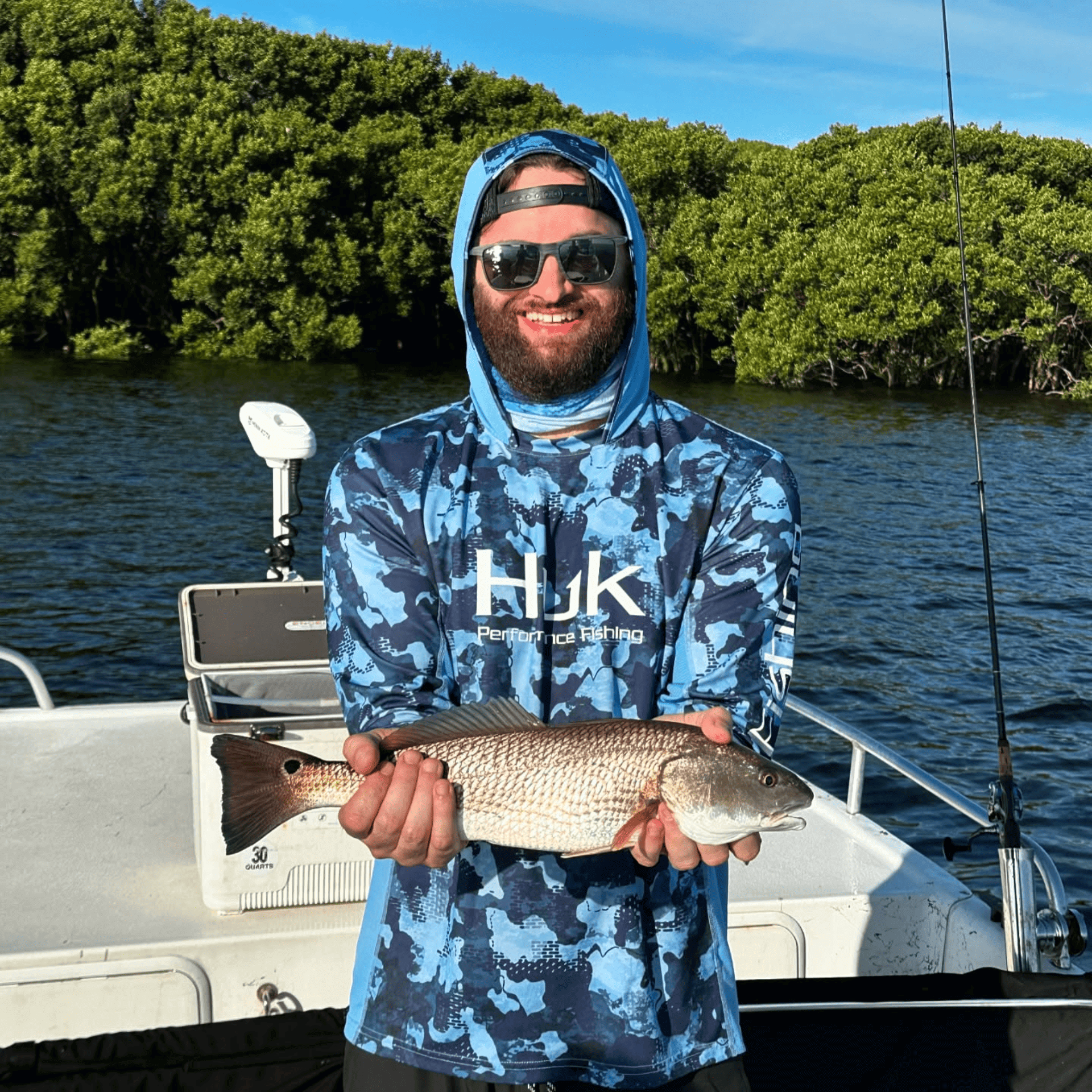A man is holding a fish in his hands on a boat.