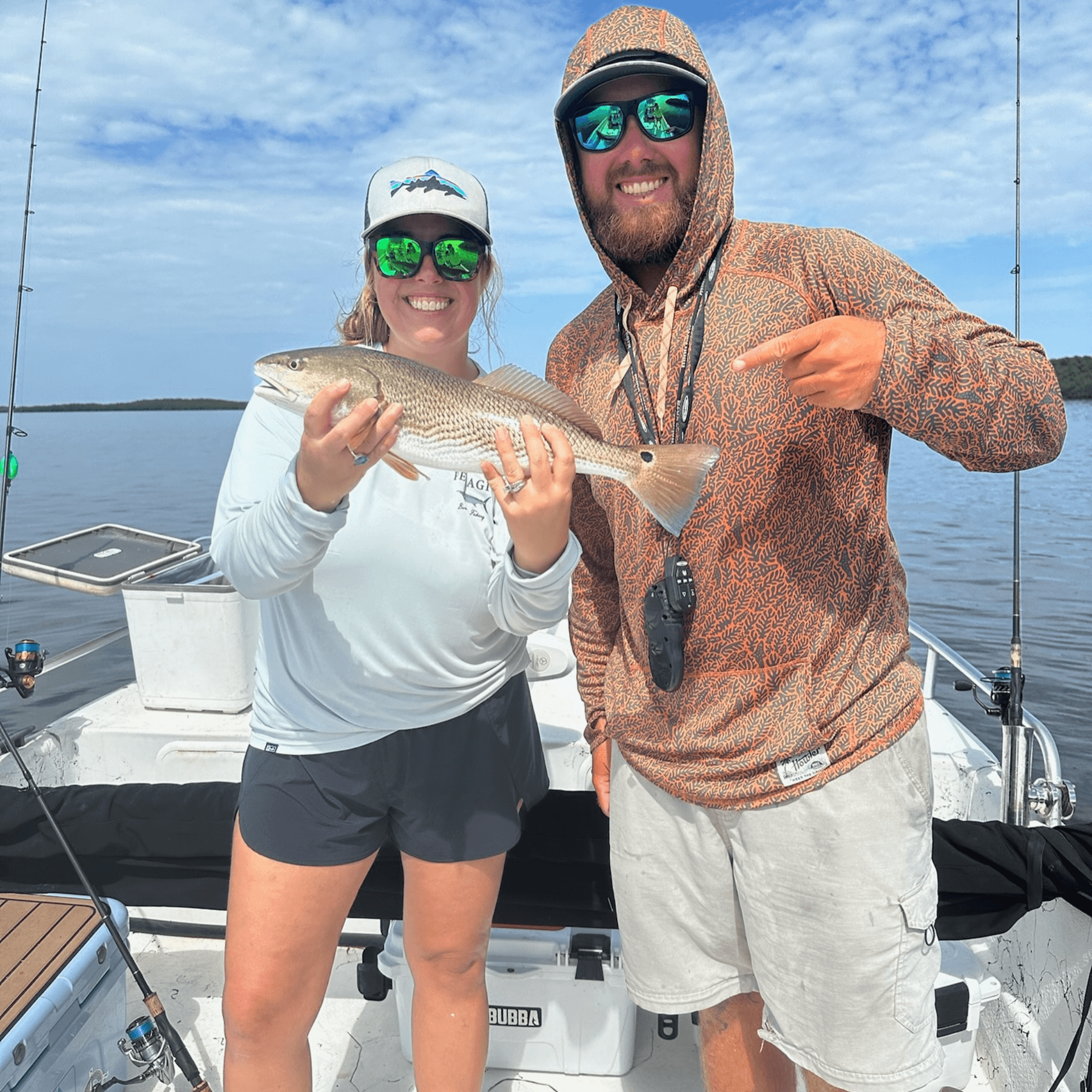 A man and a woman are standing on a boat holding a fish.