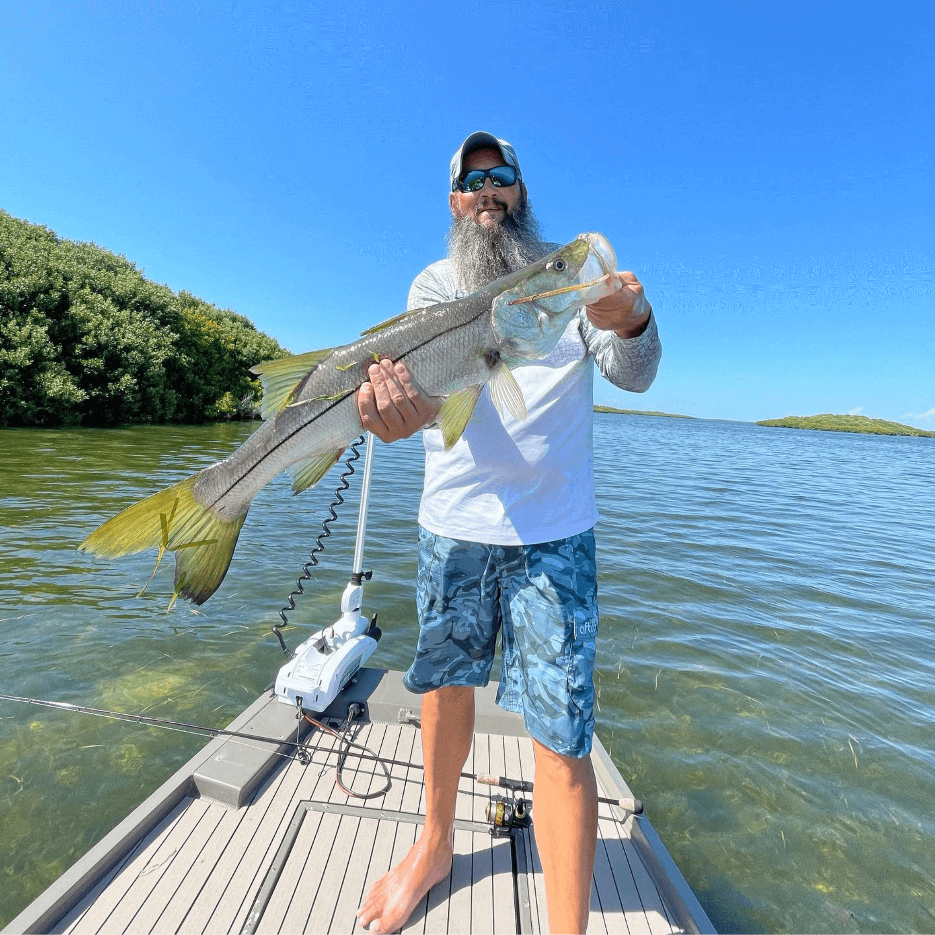 A man is standing on a boat holding a large fish