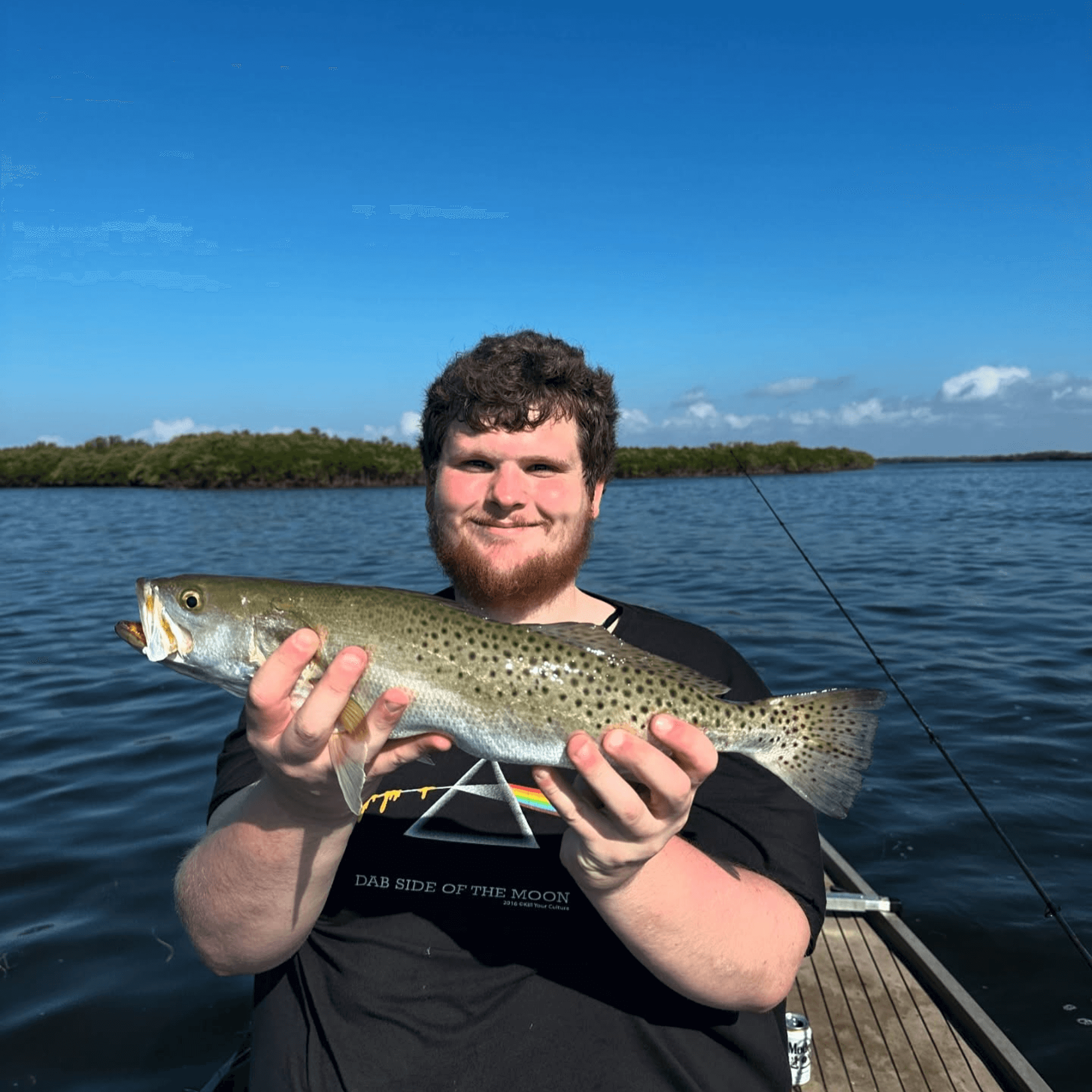 A man is holding a Crystal River Trout in his hands on a boat.